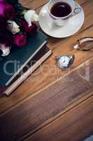 High angle view of eyeglasses by stopwatch and tea with books