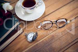 Close up of eyeglasses by stopwatch and tea with books