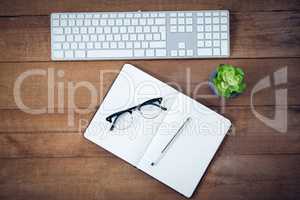 Directly above shot of diary with pen and eyeglasses by keyboard