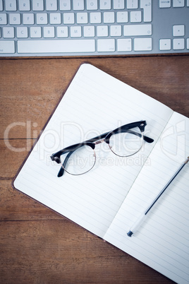 Overhead view of diary with pen and eyeglasses by keyboard