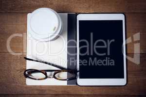 Overhead view of digital tablet with diary and eyeglasses