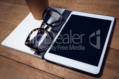 High angle view of digital tablet with diary and eyeglasses