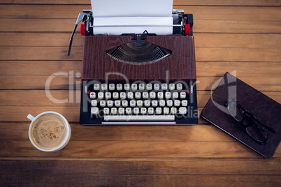 Overhead view of typewriter by coffee cup and book