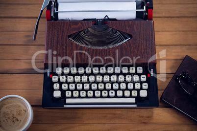 Close up of typewriter by coffee cup and book