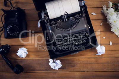 Overhead view of typewriter by telephone and crumpled papers