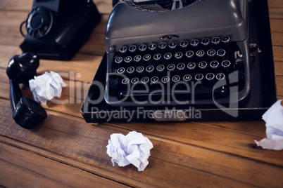 High angle view of typewriter by telephone and crumpled papers