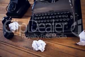 High angle view of typewriter by telephone and crumpled papers