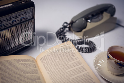 Close up of book with tea and telephone by radio