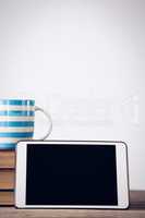 Close up of digital tablet with coffee cup on books