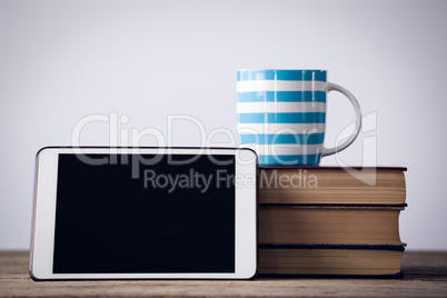 Digital tablet with coffee cup on books