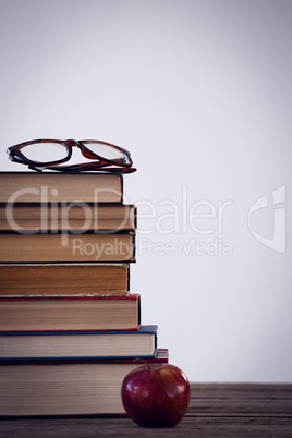 Apple by books with eyeglass on table