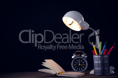 Illuminated lamp with desk organizer by alarm clock and book