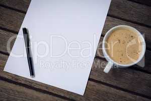 High angle view of coffee cup with paper and fountain pen