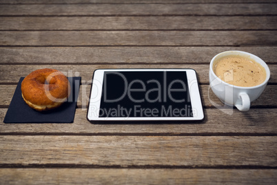 HIgh angle view of digital tablet with coffee cup donut
