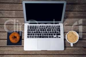HIgh angle view of laptop with coffee cup donut