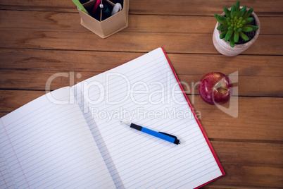 High angle view of book with pen and apple by houseplant
