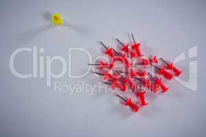 Yellow and red push pins on white background