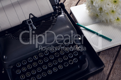 Vintage typewriter, diary and flowers on wooden table
