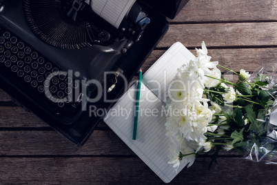 Vintage typewriter, diary and flowers on wooden table