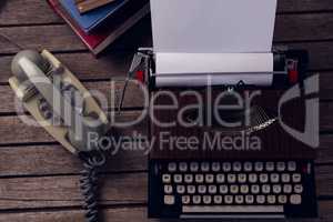 Vintage typewriter and telephone on wooden table