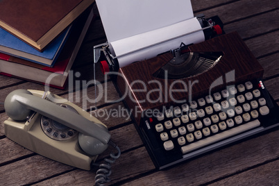 Vintage typewriter and telephone on wooden table