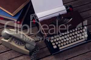 Vintage typewriter and telephone on wooden table
