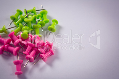 Pink and green push pins on white background