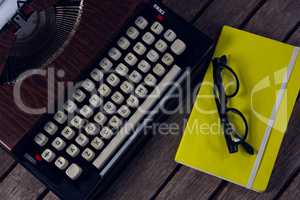 Vintage typewriter, diary and spectacles on wooden table
