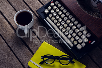 Vintage typewriter, diary, black coffee and spectacles on wooden table