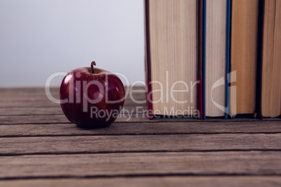 Apple and books arranged on wooden table