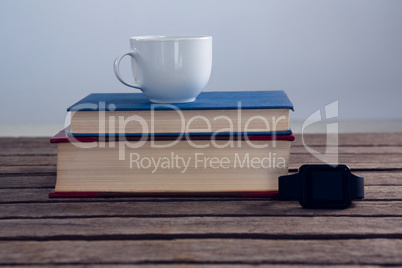 Books with cup of coffee and smart watch on wooden table