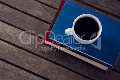 Books with cup of coffee on wooden table against white background