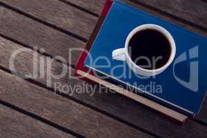 Books with cup of coffee on wooden table against white background