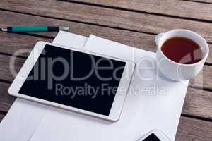 Digital tablet, black coffee and blank paper on wooden table