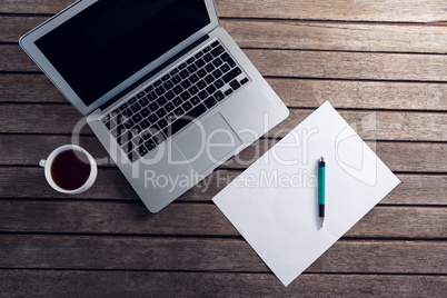 Laptop, black coffee and blank paper on wooden table