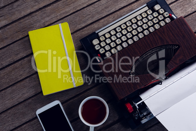 Vintage typewriter, diary, black coffee and smart phone on wooden table