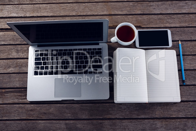 Laptop, black coffee, mobile phone and diary on wooden table