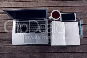 Laptop, black coffee, mobile phone and diary on wooden table