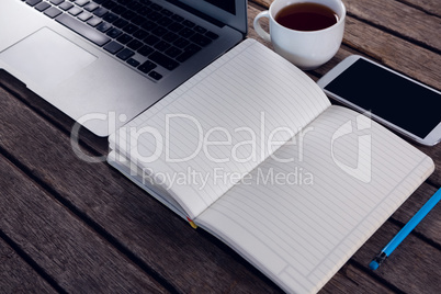 Laptop, black coffee, mobile phone and diary on wooden table