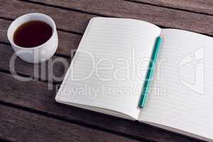 Close-up of pencil on open diary with cup of black coffee
