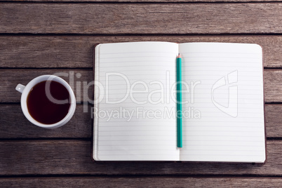 Overhead of pencil on open diary with cup of black coffee