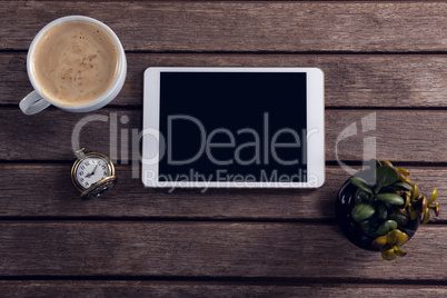 Digital tablet, coffee, pot plant and pocket watch on wooden table