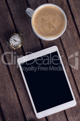 Digital tablet, coffee and pocket watch on wooden table