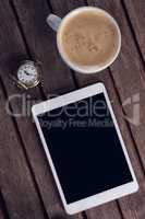 Digital tablet, coffee and pocket watch on wooden table