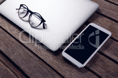 Laptop, diary, spectacles and mobile phone on wooden table