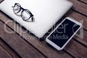 Laptop, diary, spectacles and mobile phone on wooden table