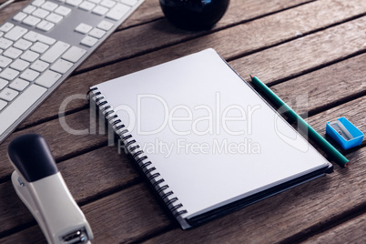 Keyboard, diary, stationery and stapler on wooden table