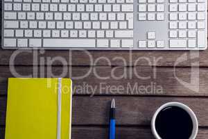 Black coffee, pen, organizer and keyboard on wooden table