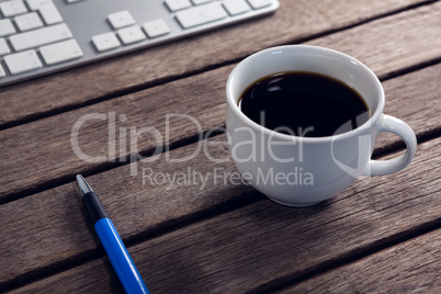 Black coffee, pen and keyboard on wooden table