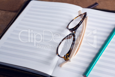 Close-up of spectacles and pencil on organizer